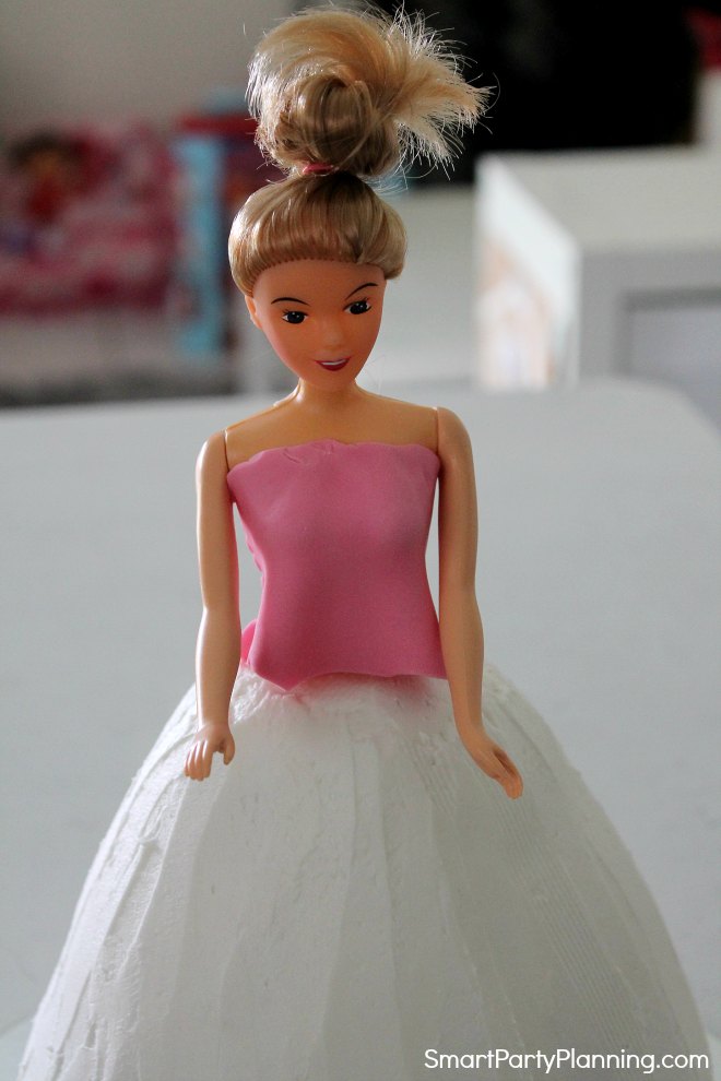 Sit the doll in the top of the cake Sit the doll in the top of the cake