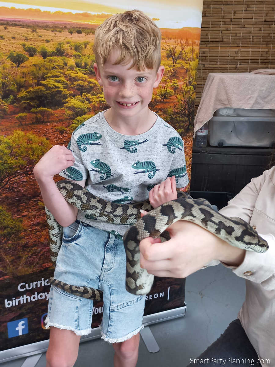 child holding a snake at a birthday party
