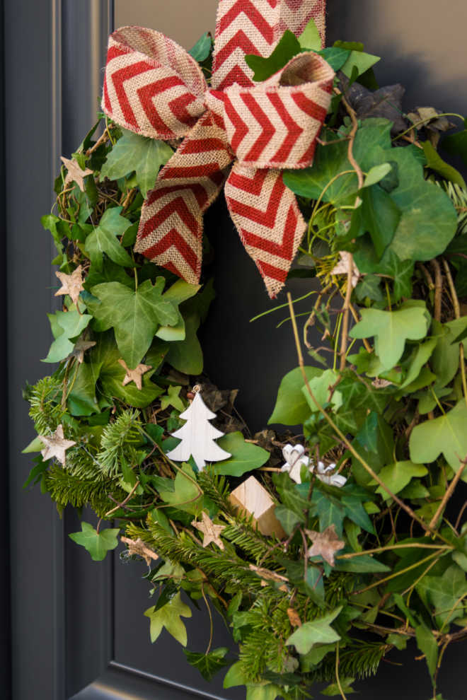 Front door with a Christmas wreath of ivy and bows.